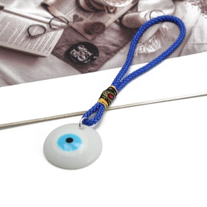 Detail of white Evil Eye charm with intricate blue braided cord and colorful accents