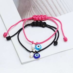 Handmade woven evil eye bracelets with pearl charms in pink and black cord style