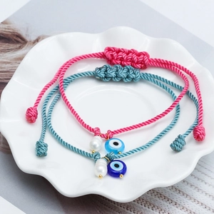 Detail of pink and blue woven Evil Eye bracelets with freshwater pearls and gold beads