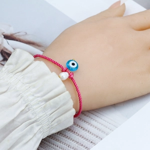 Pink braided evil eye bracelet with blue glass charm and white pearl accent for women