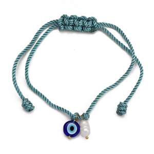 Close-up of woven Evil Eye bracelet with blue glass bead and white baroque pearl