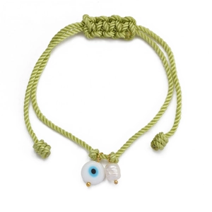 Detail of hand-woven light green evil eye bracelet with white pearl and gold charms