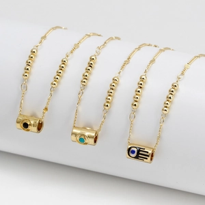 Detaillierte Makroansicht von bunten Emaille-Augen und Hamsa-Hand-Anhängern an Goldperlenkette