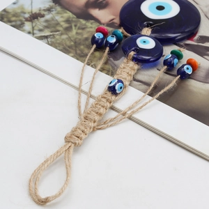 Detail of woven rope Evil Eye pendant with colorful wooden beads and glass charms