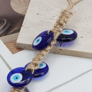Pendentif mural œil bleu en verre avec corde en jute naturelle sur une surface en pierre