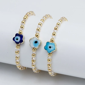 Détail de trois bracelets perlés dorés avec breloques œil de protection en forme de fleurs