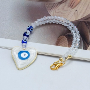 Détail macro du pendentif œil porte-bonheur en cristal avec cœur et chaîne dorée