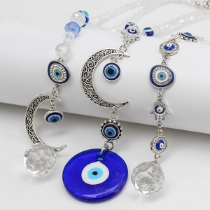Detailed macro view of the evil eye hamsa charm with blue glass and moon pendant