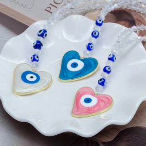 Détail de pendentifs cœur mauvais œil en blanc, bleu et rose sur une assiette blanche