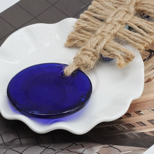 Macro detail of Evil Eye glass pendant with rustic jute rope on a white ceramic plate