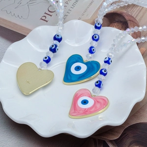 Détail macro du pendentif coeur Evil Eye avec émail bleu et perles en cristal facettées