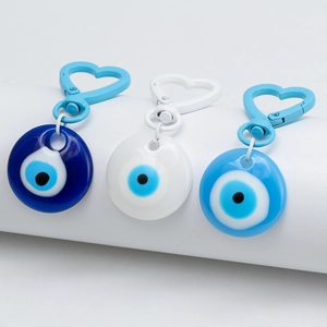 Detailed close-up of heart-shaped metal clasps and blue evil eye charms on three keychains