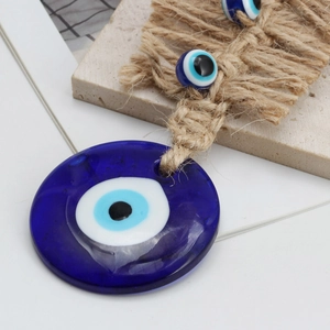 Detail of blue glass Evil Eye pendant with hand-woven jute rope and small beads