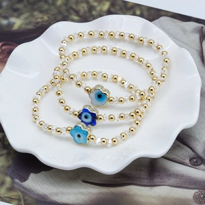 Bracelet trois pièces en perles dorées avec œil grec et fleurs en cristal sur assiette