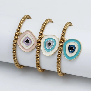 Vue détaillée de trois bracelets à perles dorées avec charms oeil protecteur en émail