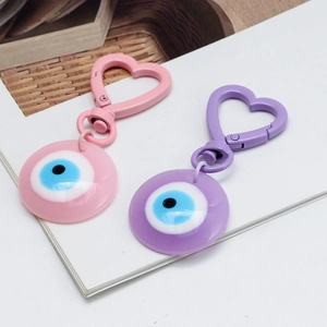 Pink and purple heart-shaped evil eye keychains with resin eye pendants on white background