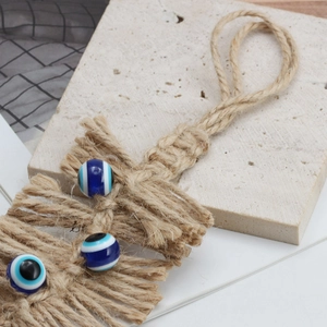 Bohemian handmade macrame wall hanging featuring three blue evil eye beads on jute rope