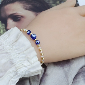 Vue détaillée du bracelet Evil Eye avec perles bleues et boules en métal doré poli