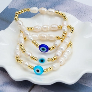 Detailed view of three-piece Evil Eye pearl bracelet set on shell porcelain plate