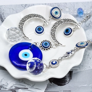 Detailed macro of Evil Eye moon pendant featuring blue glass bead and crystal ball hanging