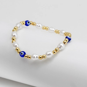 Close-up of evil eye beaded bracelet with white pearls and gold metal beads