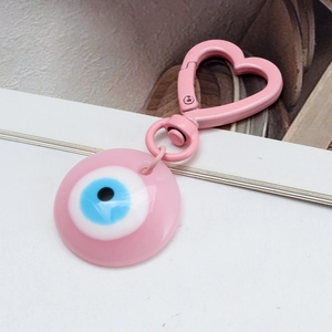 Macro detail of a pink evil eye keychain featuring a heart-shaped metal spring clasp