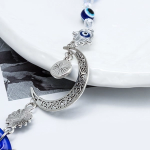Detailed view of silver moon pendant with Hamsa hand and blue Evil Eye lucky beads
