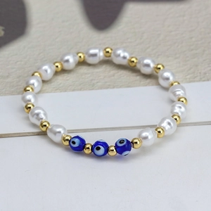 Macro shot of baroque pearls and blue evil eye charms on an elastic beaded bracelet