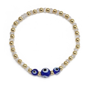 Détail d'un bracelet de perles dorées et de charmes bleus contre le mauvais oeil