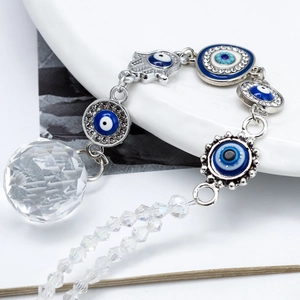 Detail of blue evil eye charms with clear crystal prism ball on white ceramic tray
