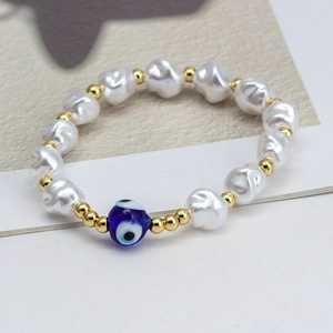 Detailed macro view of baroque pearls and golden metal beads with blue evil eye charm
