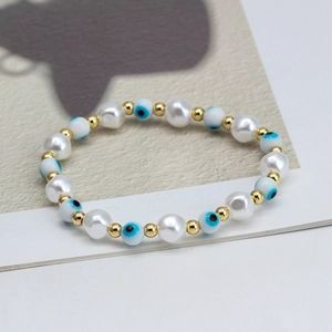Detail of beaded evil eye bracelet with white faux pearls and golden spacers on a magazine