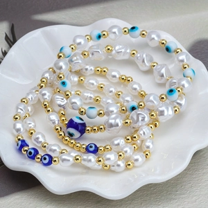 Bohemian Evil Eye beaded bracelet set with white pearls and gold accents in a shell dish