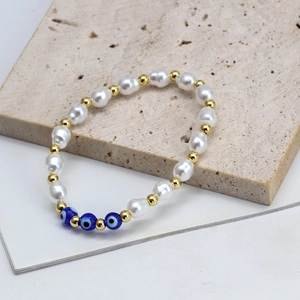 Bohemian pearl bracelet with evil eye beads and gold accents on a stone background