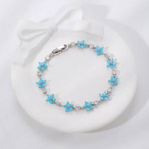 Elegante bracciale d'argento con fiori blu e zirconi su un vassoio di ceramica