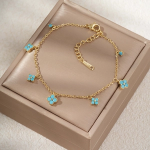 Elegante pulsera de acero inoxidable dorado con cinco dijes de trébol turquesa y cierre