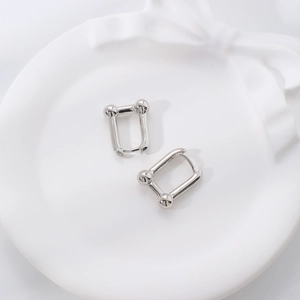 Silver minimalist U-shaped horseshoe hoop earrings displayed on a white ceramic tray