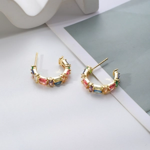 Detailed macro view of C-shaped gold-plated studs with rainbow baguette-cut zircon stones
