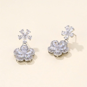 Detail of silver plum blossom earrings with pear-cut zircon crystals and a polished finish