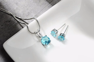 Detailaufnahme von blauem Zirkonia-Halsketten und Ohrring-Set auf weißem Tablett