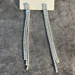 Detail view of silver tassel drop earrings with sparkling rhinestones on grey display