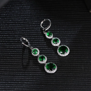 Detailed macro view of triple-tier emerald green crystal drop earrings in silver setting