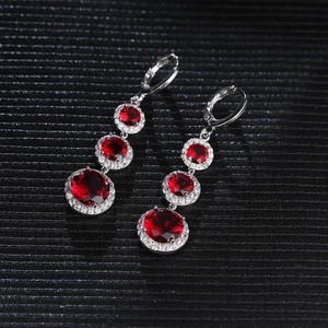 Macro shot of silver drop earrings featuring triple-stacked red gemstones with halo diamonds