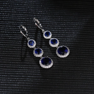 Detailed macro view of silver drop earrings featuring deep blue stones and white crystals