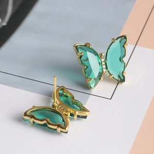 Boucles d'oreilles papillon dorées avec cristaux verts et détails en zircon