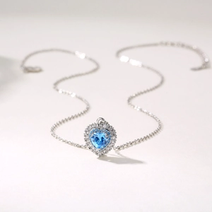 Detailansicht des herzförmigen blauen Edelsteinanhängers mit Diamantrand an der Silberkette