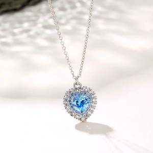Makroaufnahme der Heart of the Ocean Kette mit blauem Herzkristall und Halo-Fassung