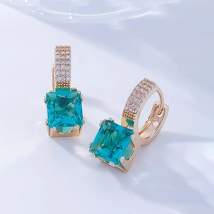 Vue macro de boucles d'oreilles en or avec gemme vert-bleu rectangulaire et pavé de diamants