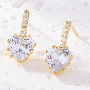 Détails macro de boucles d'oreilles cœur dorées avec incrustation de zircon blanc