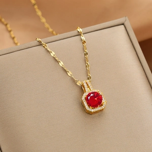 Close-up of golden necklace with a red square zircon pendant and sparkling white micro-stones